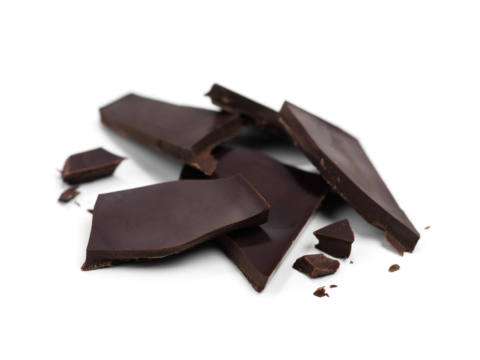 A photo of several pieces of dark chocolate laid on a white surface against a white background
